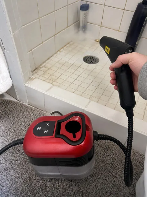 Customer using the red steam cleaner on bathroom tile grout