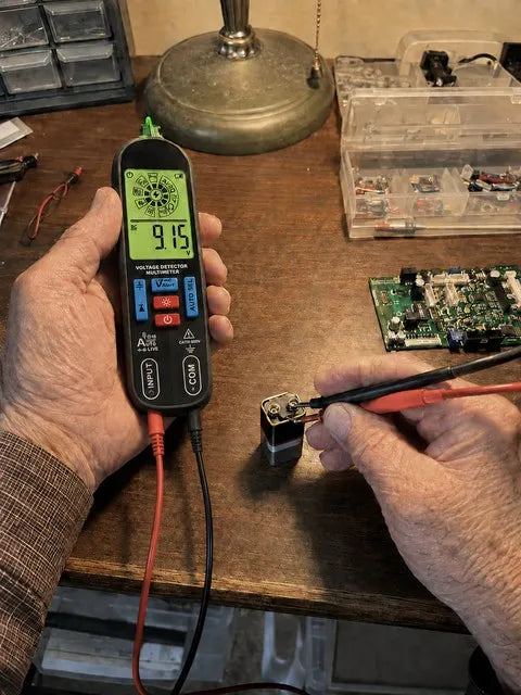 Smart pen multimeter checking a battery at a home electronics desk