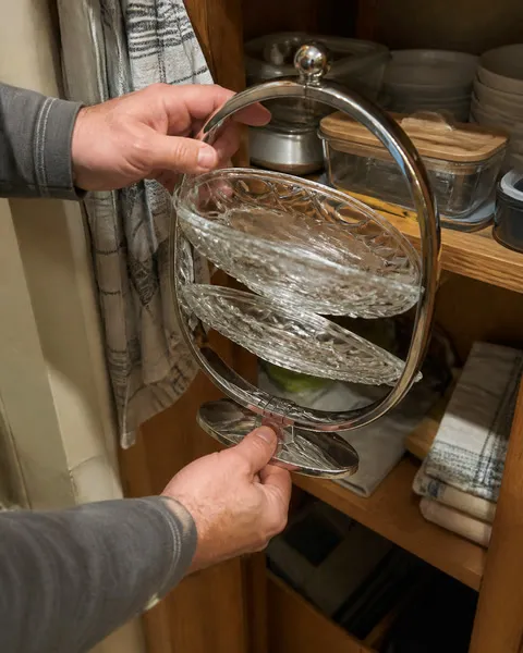 Hands folding the serving stand for storage in a dining hutch