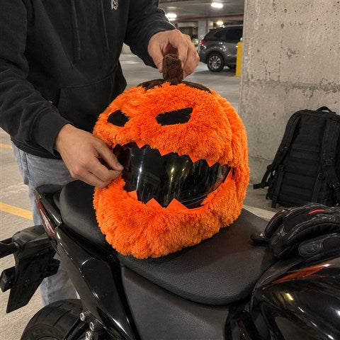 Rider adjusting a Pumpkin-style cover over a helmet in a parking garage