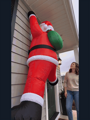 Light-up wall-climbing Santa transitioning from daylight to an illuminated evening display