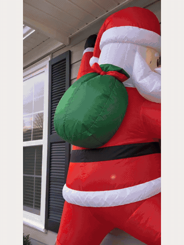 Light-up wall-climbing Santa inflatable glowing on a home exterior