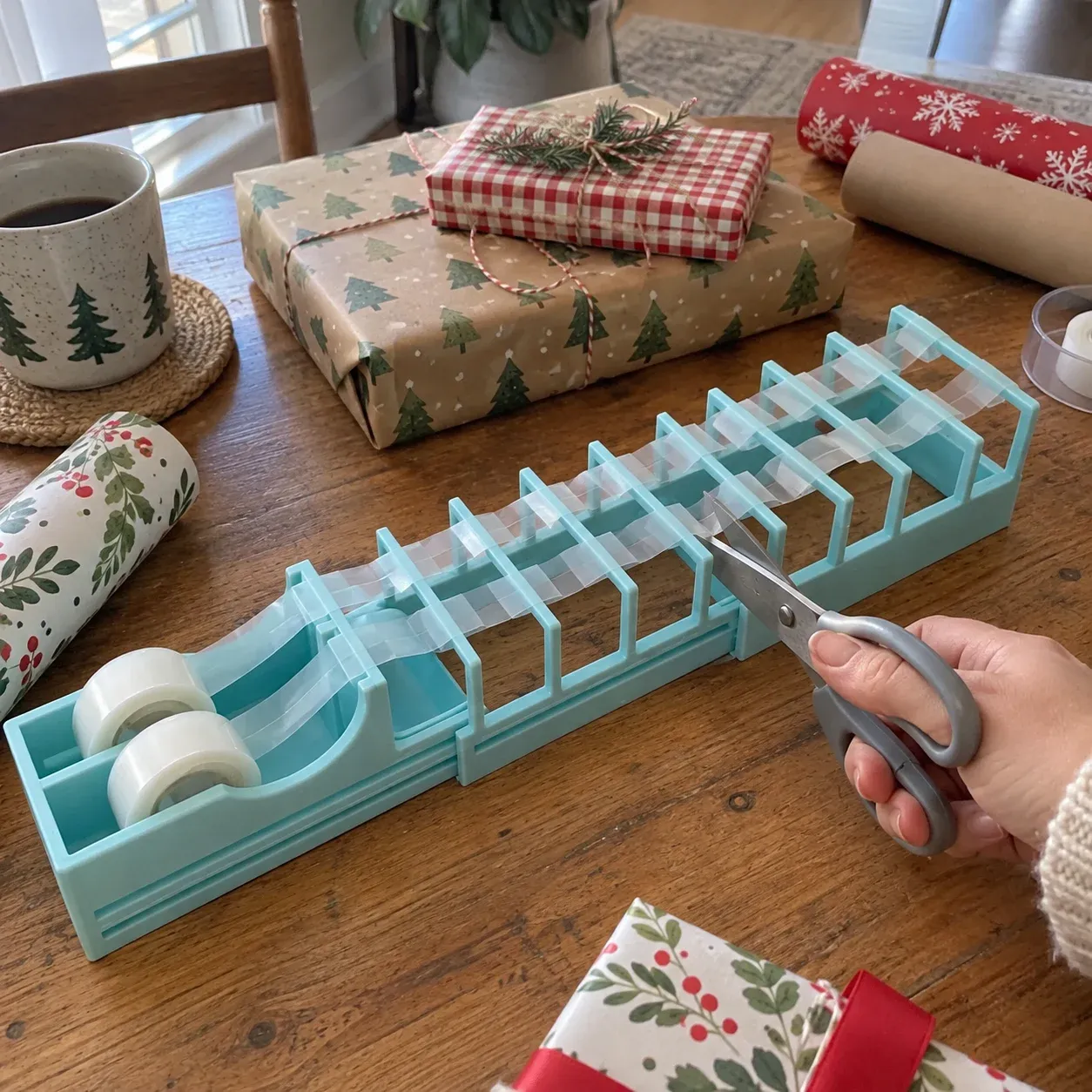 Tape prep station on a home wrapping table while scissors cut between the raised guide bars