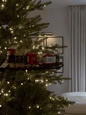 Hanging Christmas tree train moving around a decorated tree with light and mist