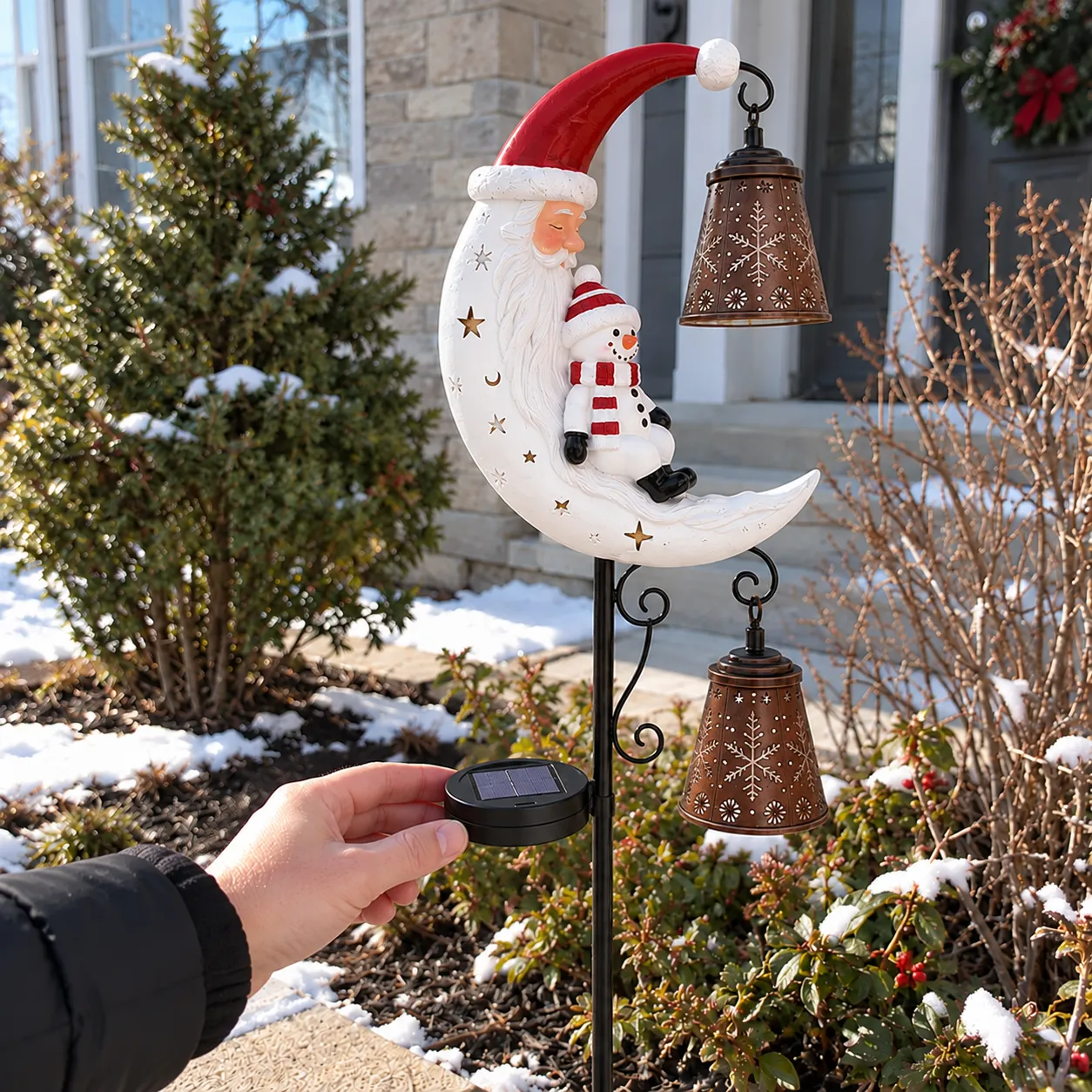 Hand checking the mounted solar panel on the Santa and snowman moon garden light in a snowy front yard