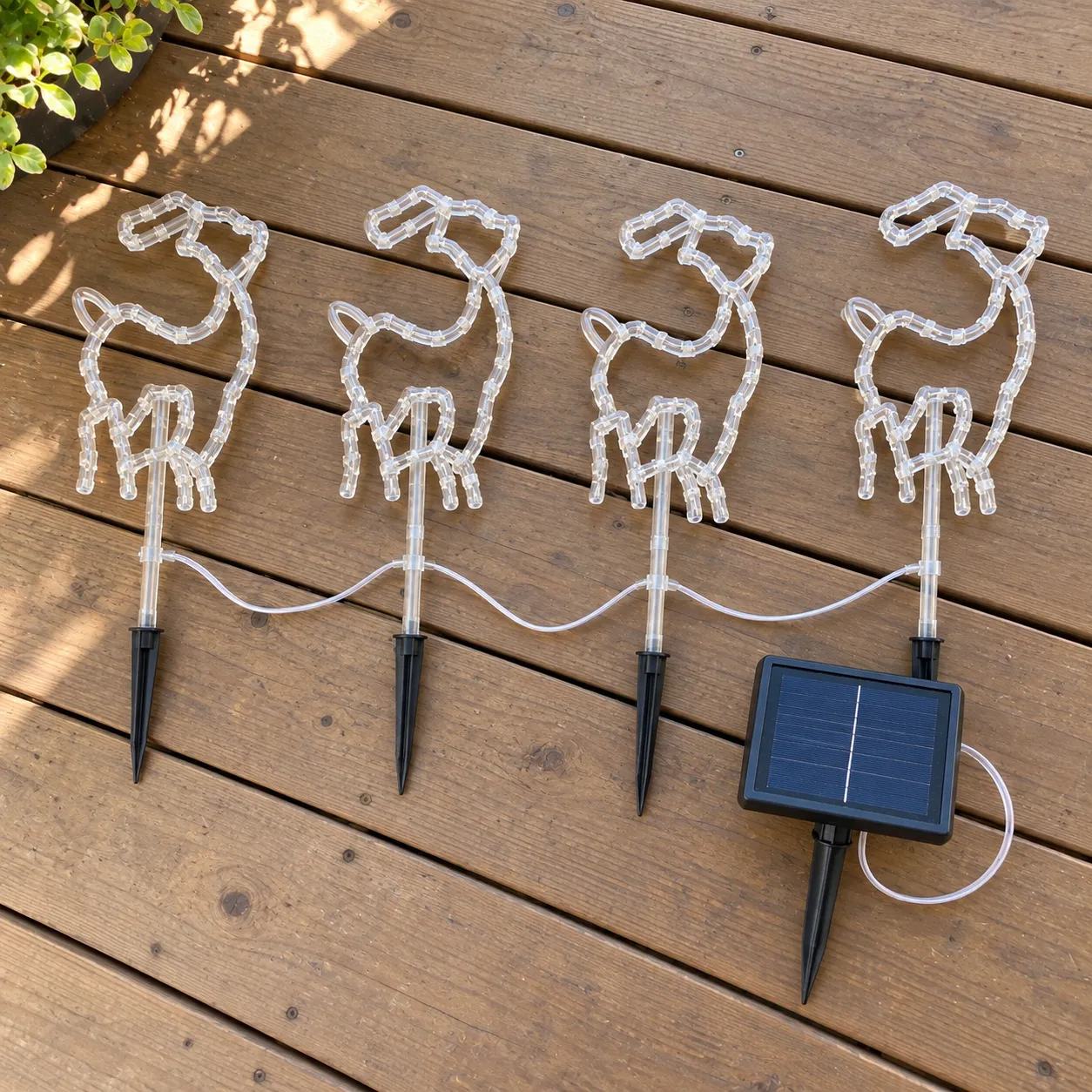 Four connected reindeer lights and one solar panel arranged on a wooden porch
