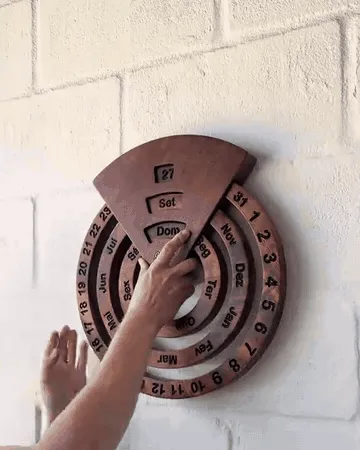 Hands rotating the wooden calendar rings to update the day, month, and weekday