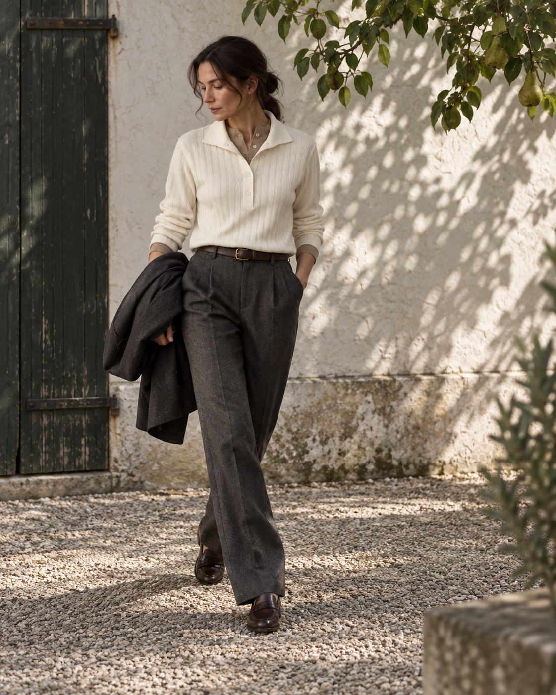 The Contrast-Collar Polo styled with charcoal trousers in a courtyard, editorial view.