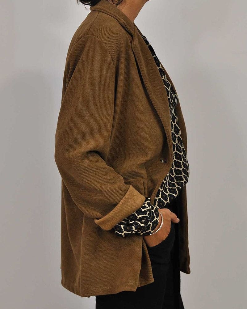 Side view of camel cardigan showing geometric blouse cuffs and sleeve detail