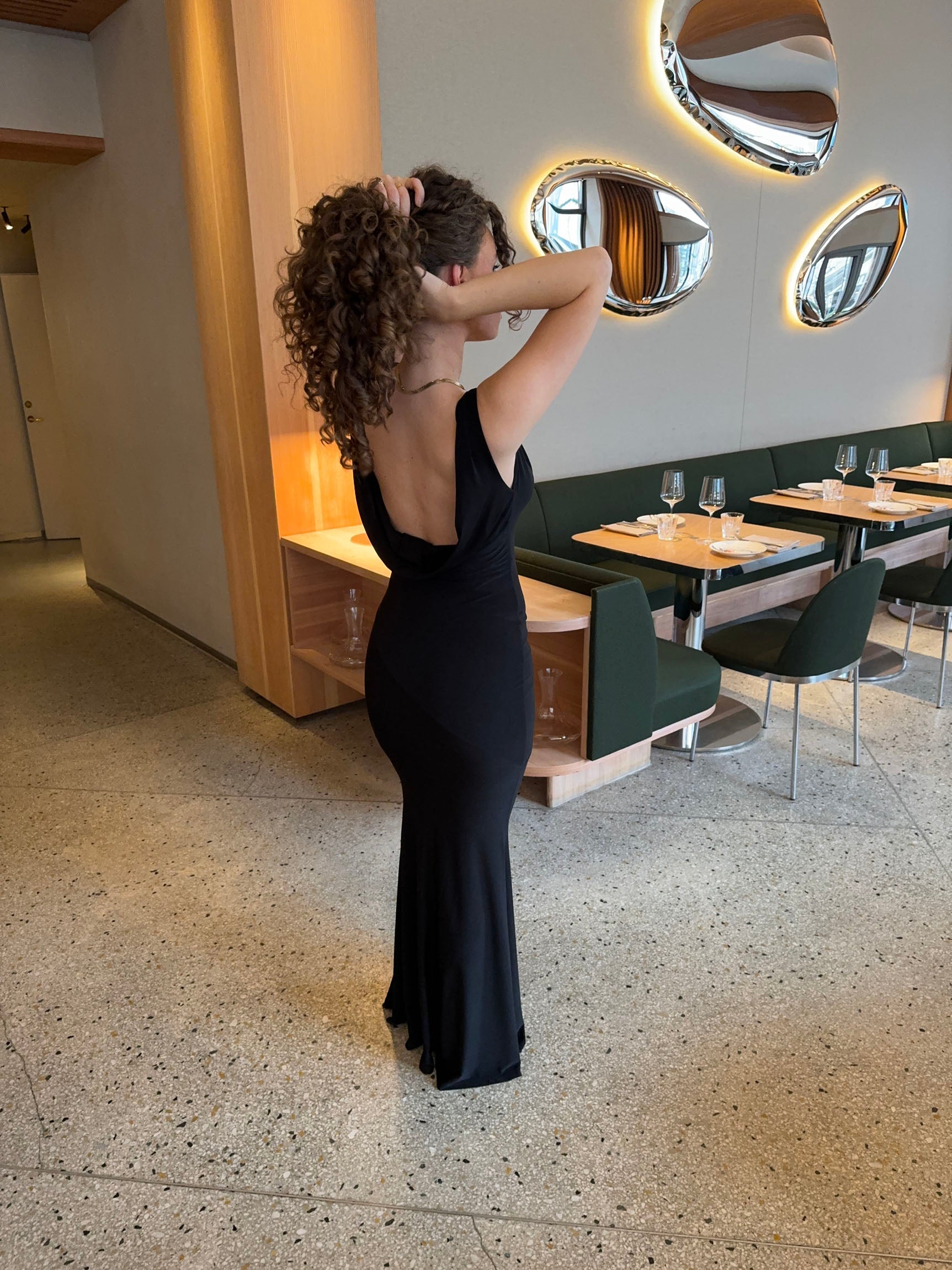 Back view of black maxi dress showing open backless cut and floor-length hem