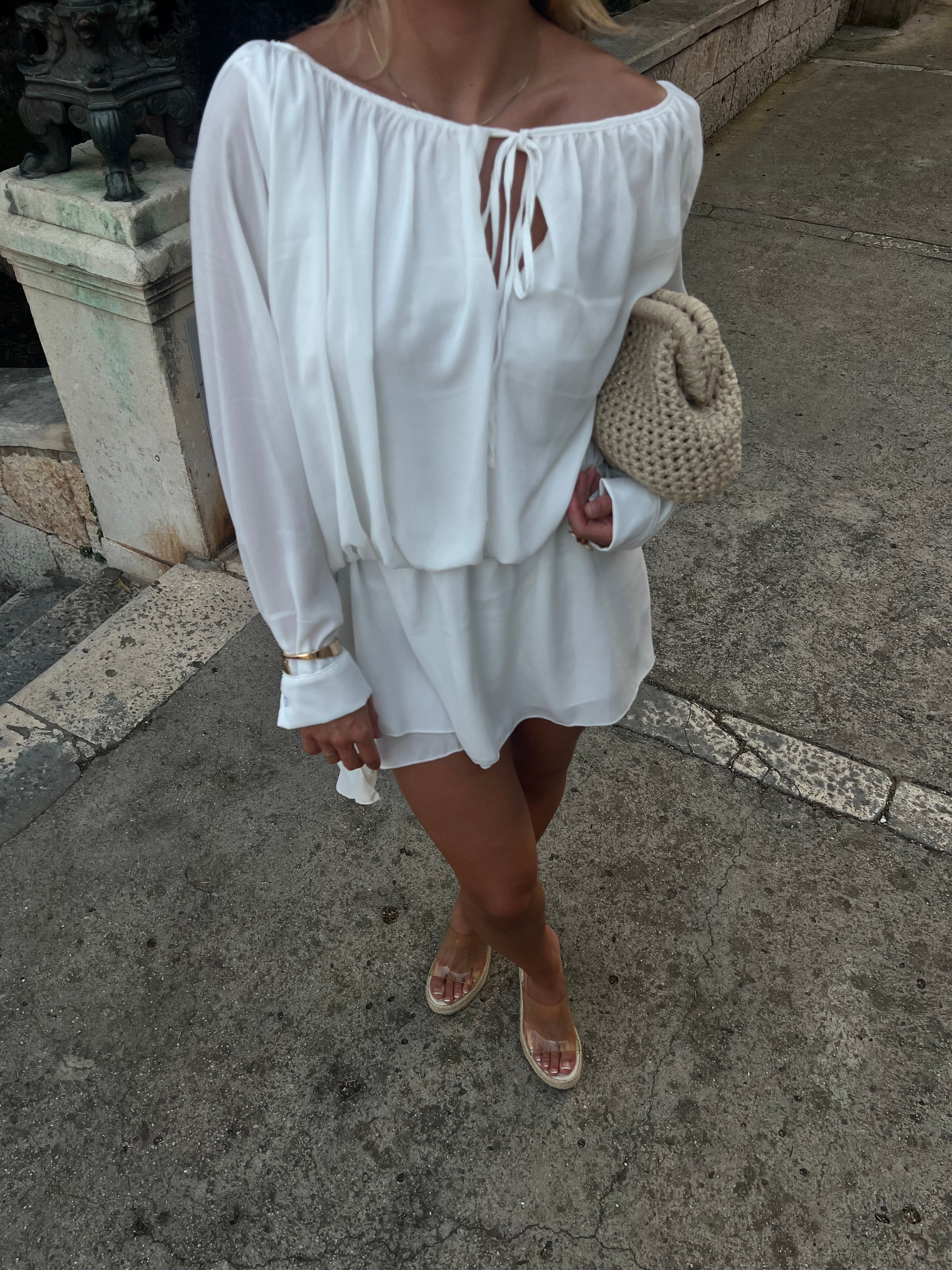 White off-shoulder ruffle mini dress with long billowed sleeves and tie closure
