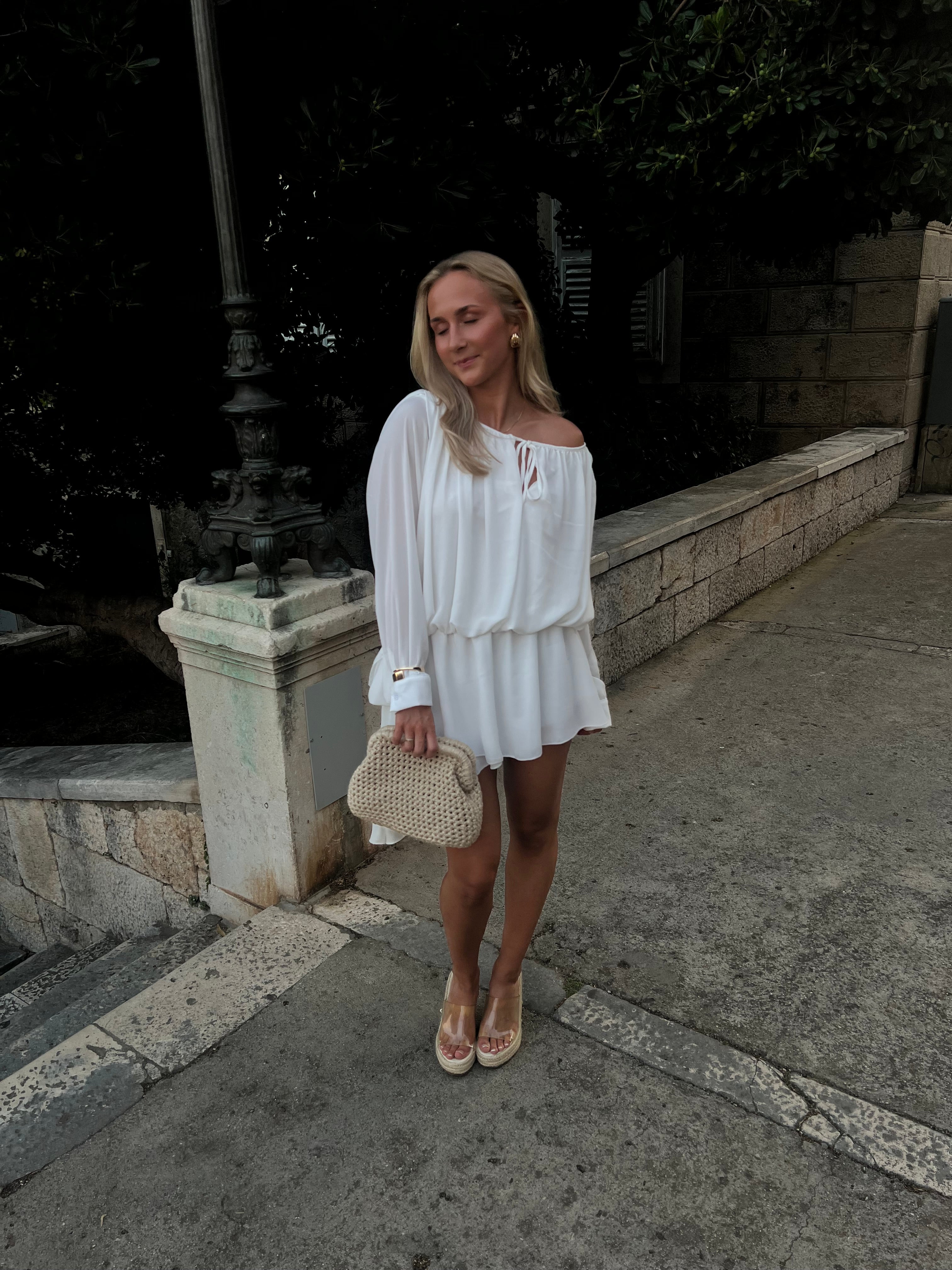 White off-shoulder ruffle mini dress with long puffed sleeves and tie detail