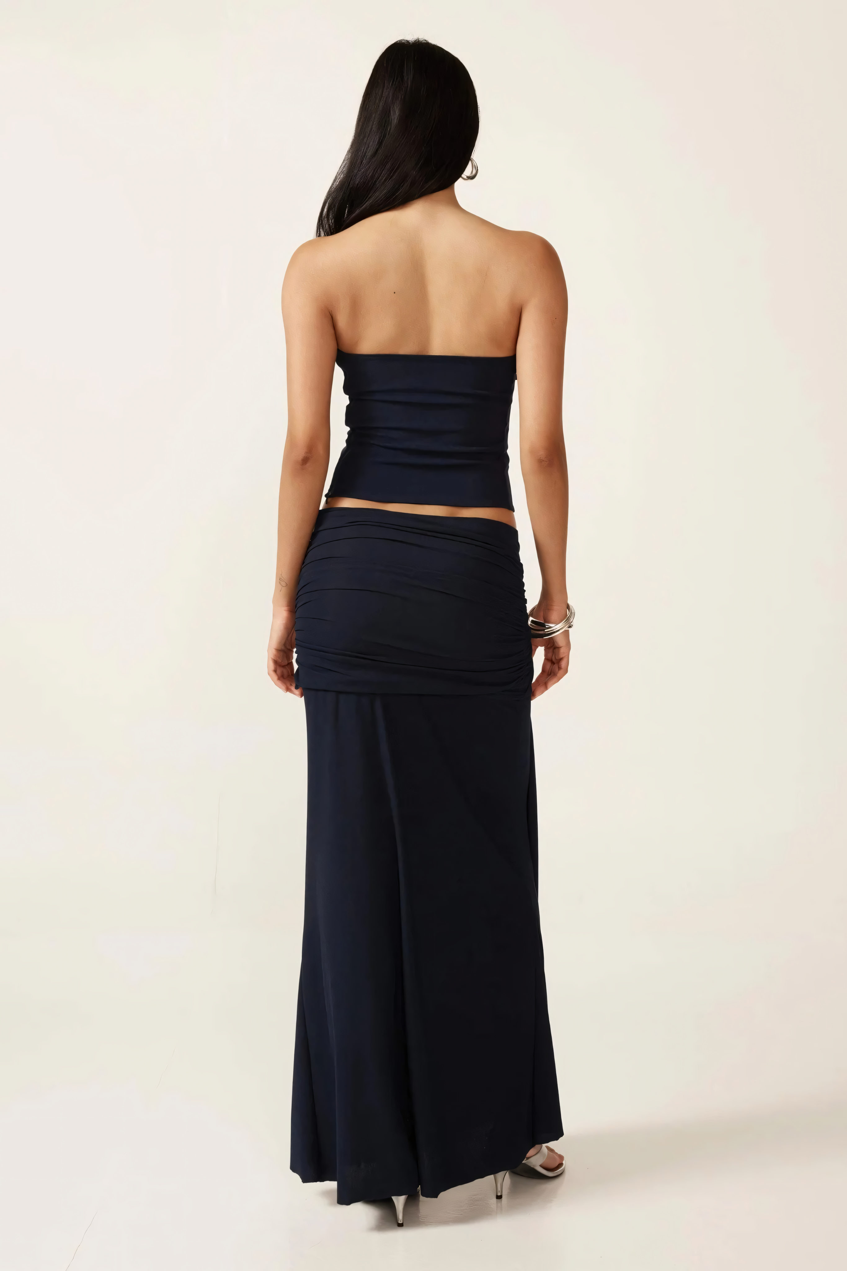 Back view of navy two-piece ruched set showing strapless crop top and floor-length skirt