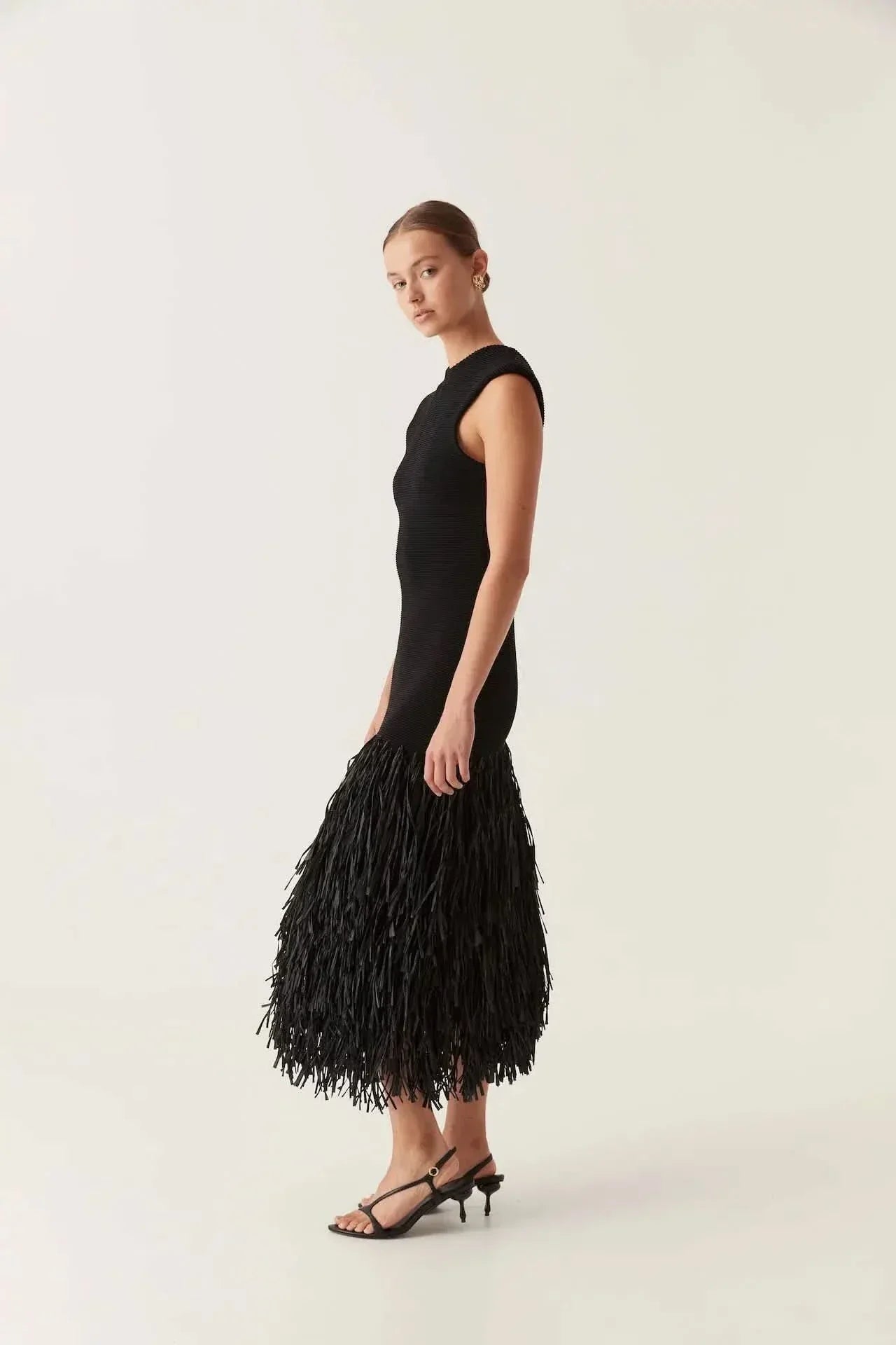 Side profile of black fringe midi dress showing fitted bodice and movement