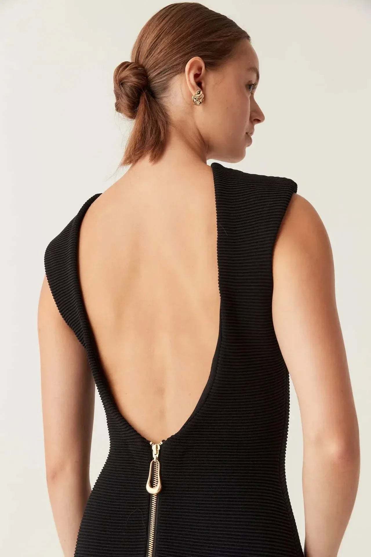 Close-up detail of knit texture and gold zipper closure on V-back