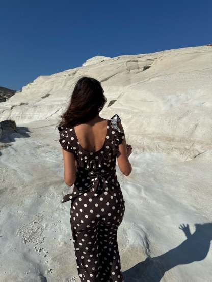 Back view of brown polka dot maxi dress showing open back and ruffle sleeves