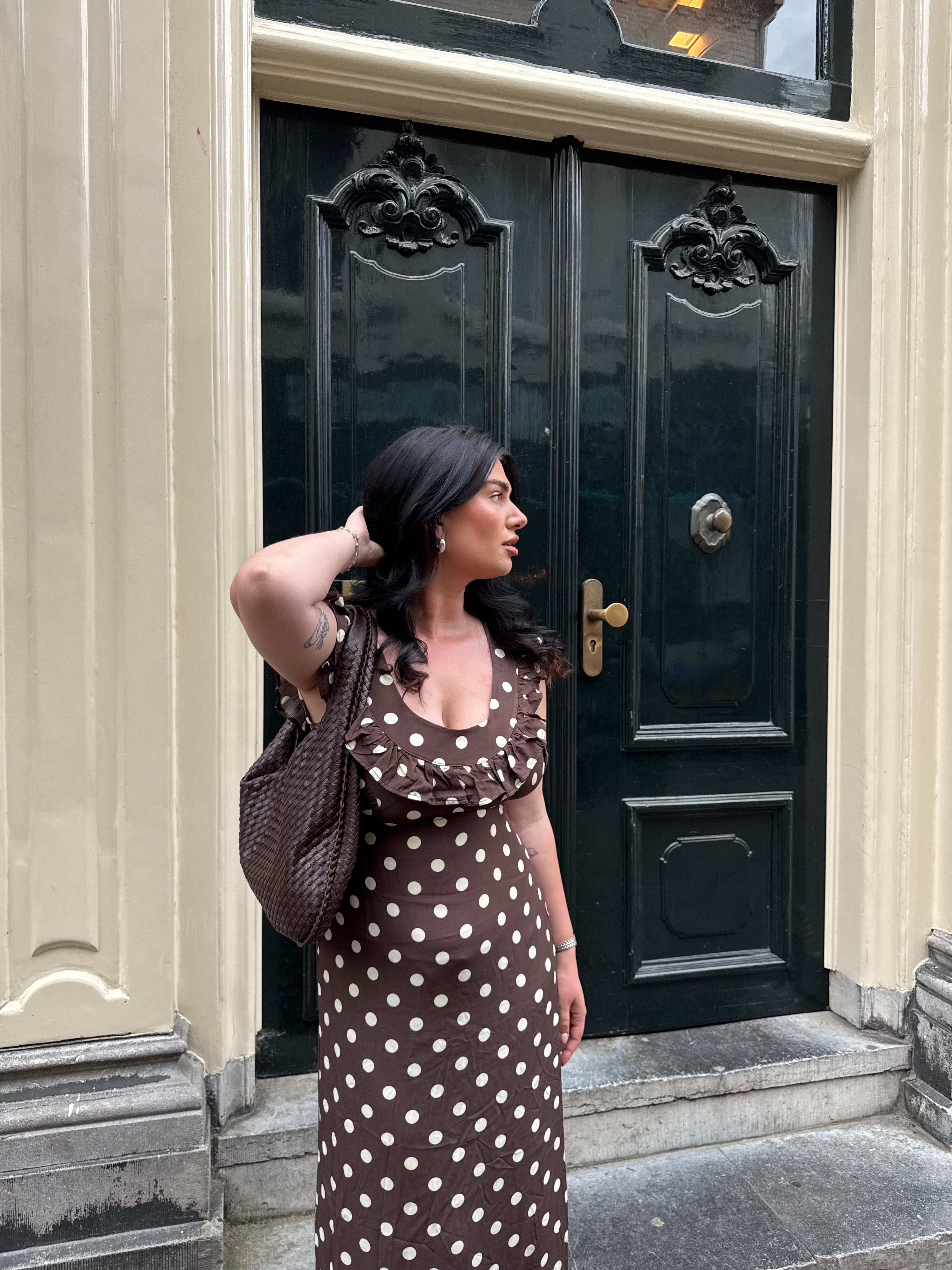 Brown polka dot maxi dress with ruffle sleeves worn with crossbody bag