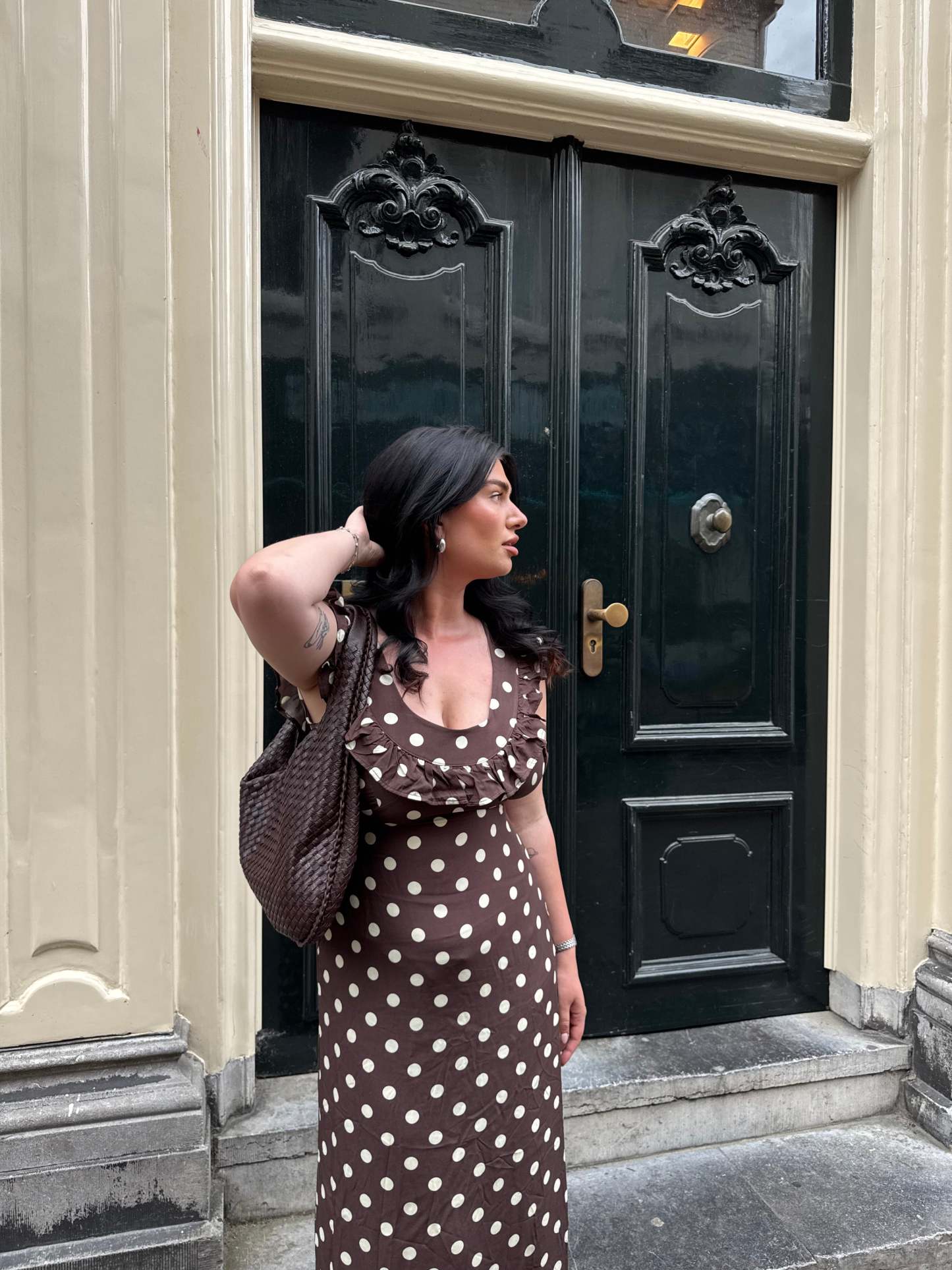 Brown polka dot maxi dress with ruffle sleeves worn with crossbody bag