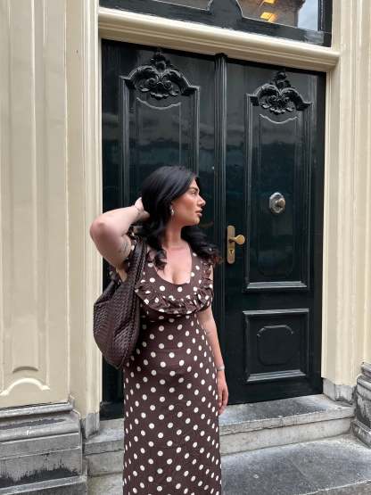 Brown polka dot maxi dress with ruffle sleeves worn with crossbody bag
