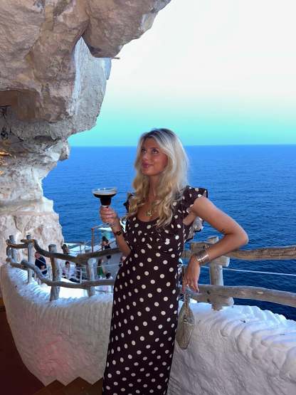 Brown polka dot maxi dress with ruffle sleeves at coastal location with ocean view