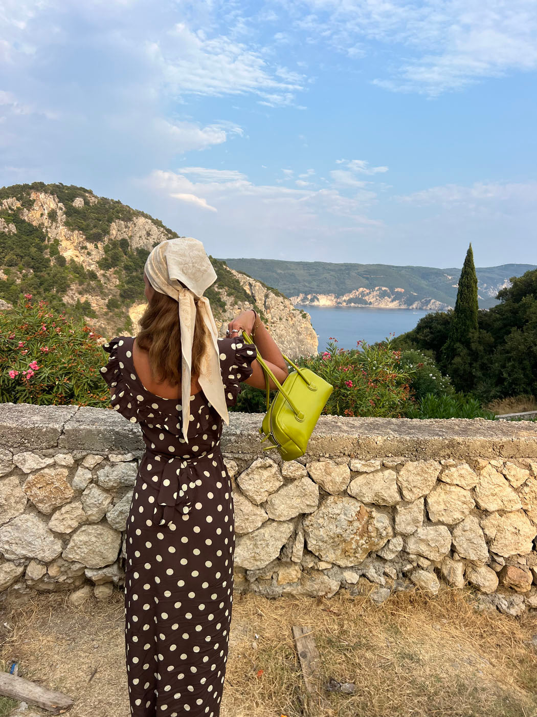 Back view of brown polka dot maxi dress at scenic coastal location