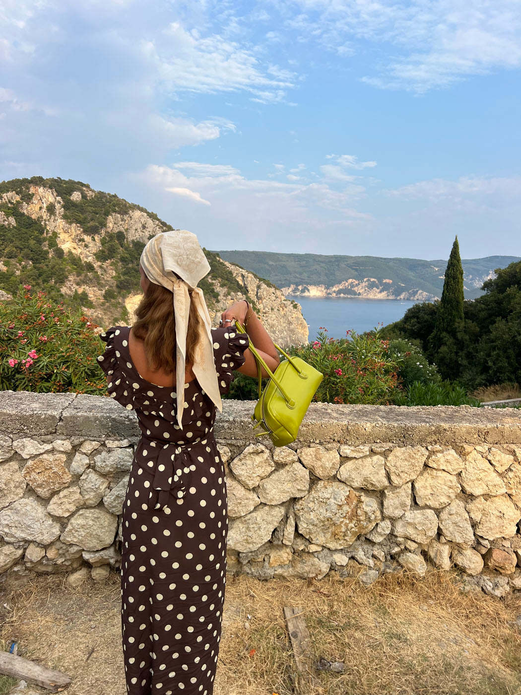 Back view of brown polka dot maxi dress at scenic coastal location