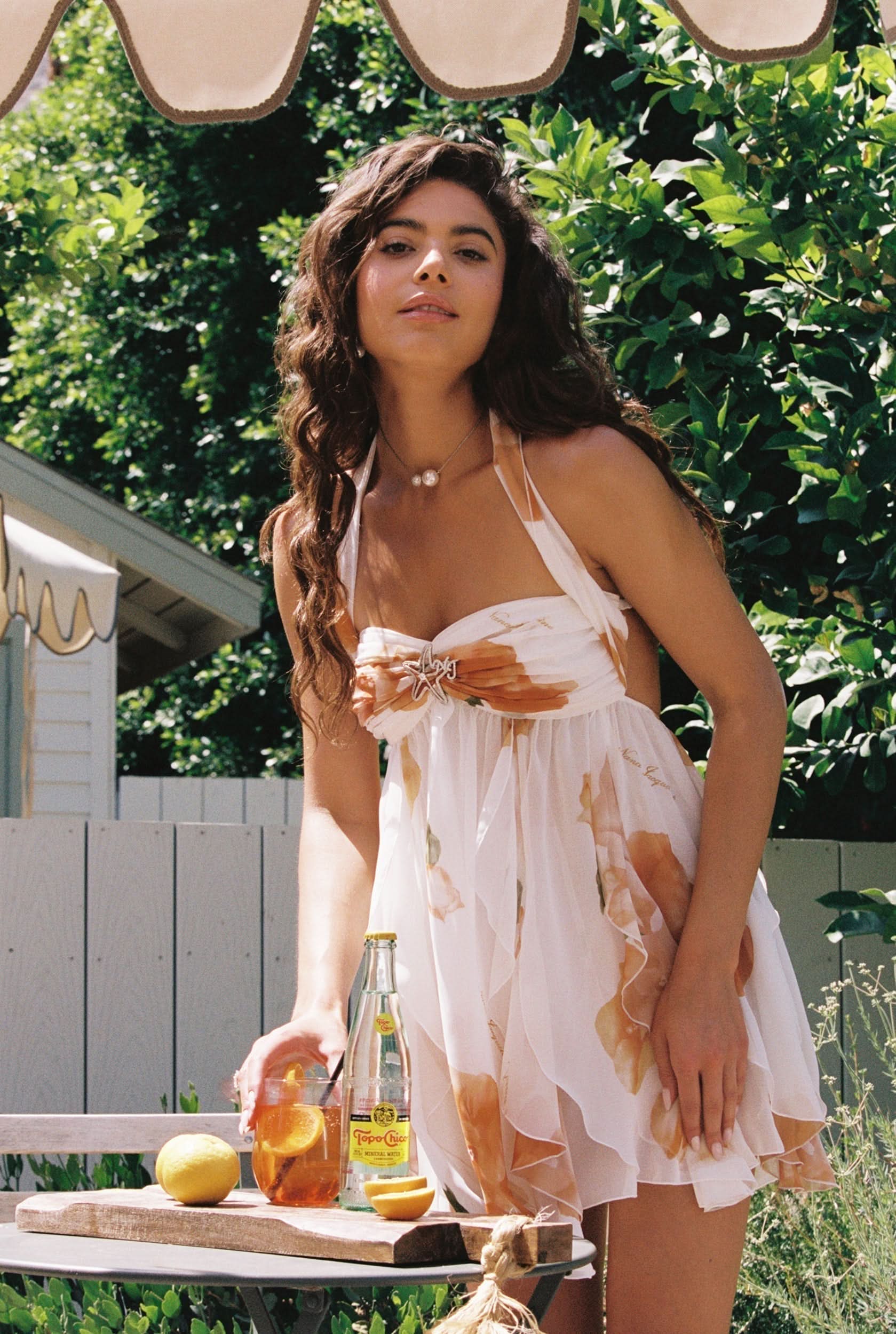 Cream halter mini dress with orange floral ruffles and star buckle detail