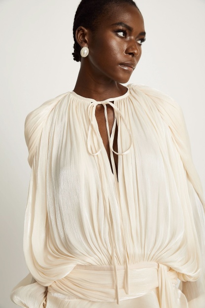 Cream ruffle mini dress detail showing pleated fabric and ruffled skirt
