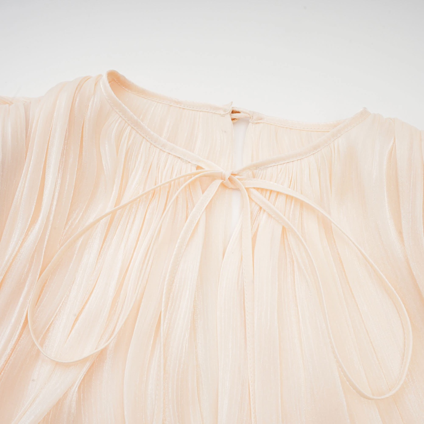 Close-up of cream pleated ruffle neckline with gathered fabric detail