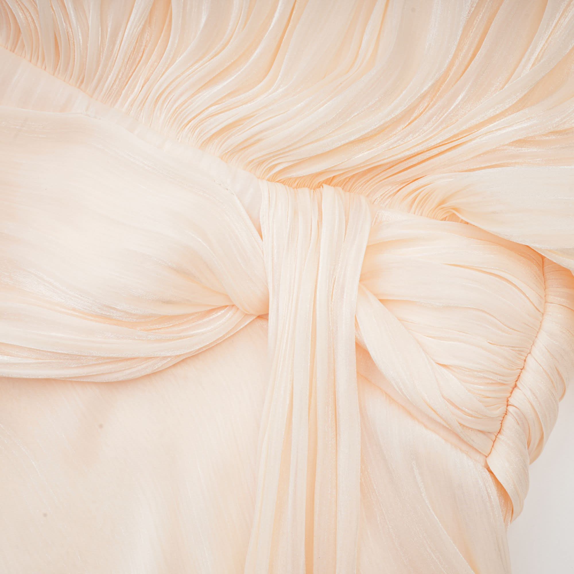 Detailed view of cream ruffle cape with fine pleating and layered texture