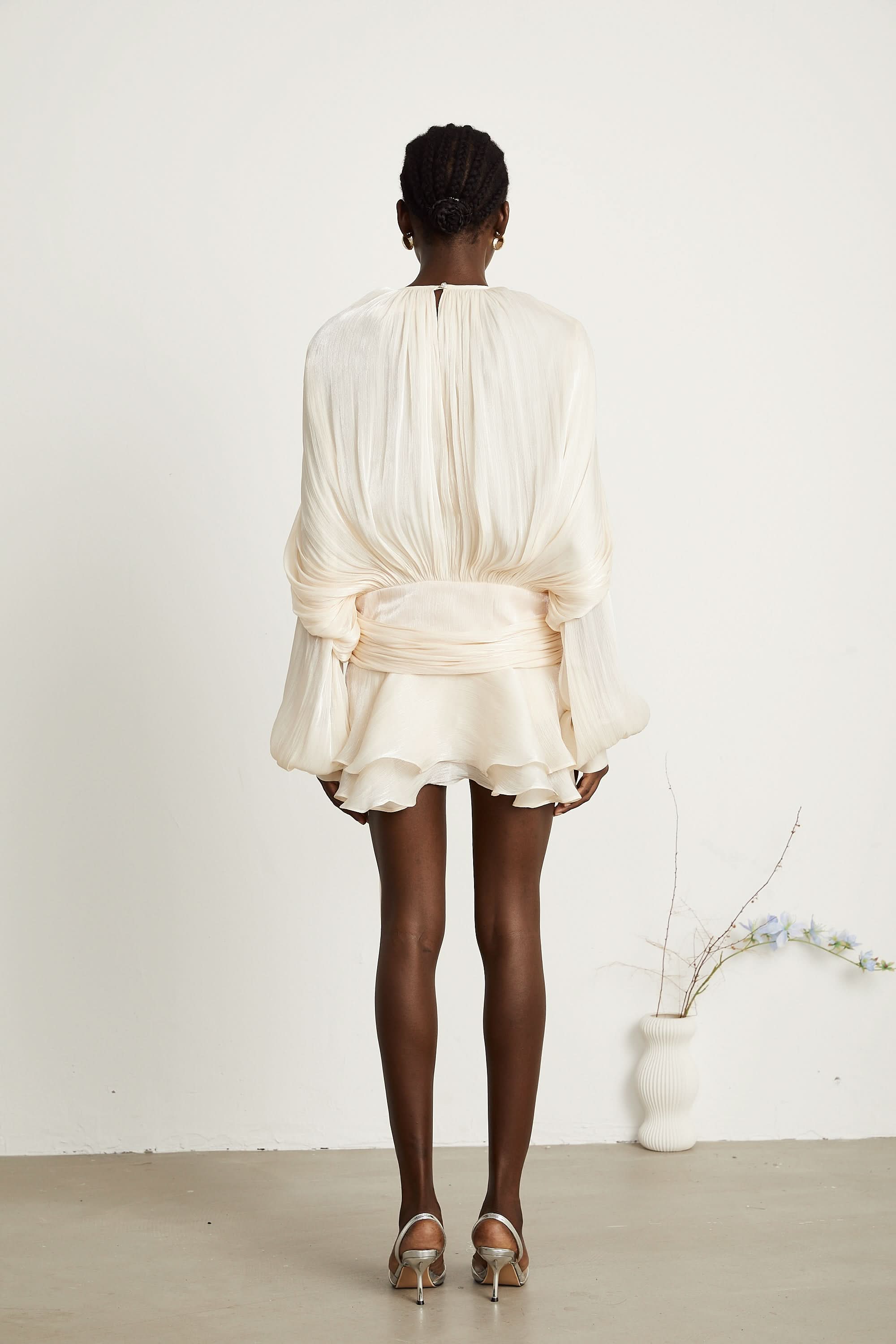 Back view of cream ruffle mini dress with gathered waist detail