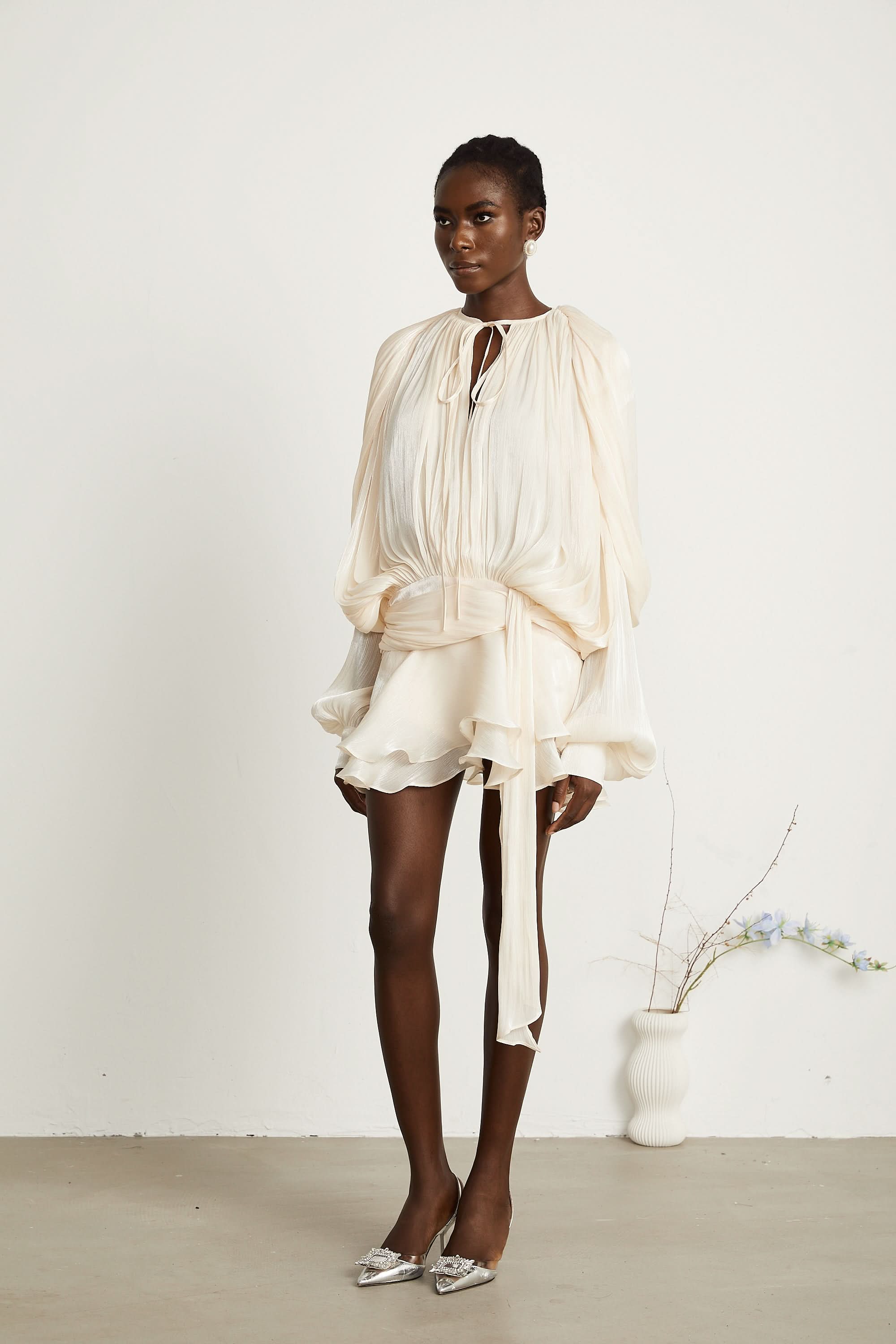 Cream pleated mini dress with tie waist and layered ruffle skirt