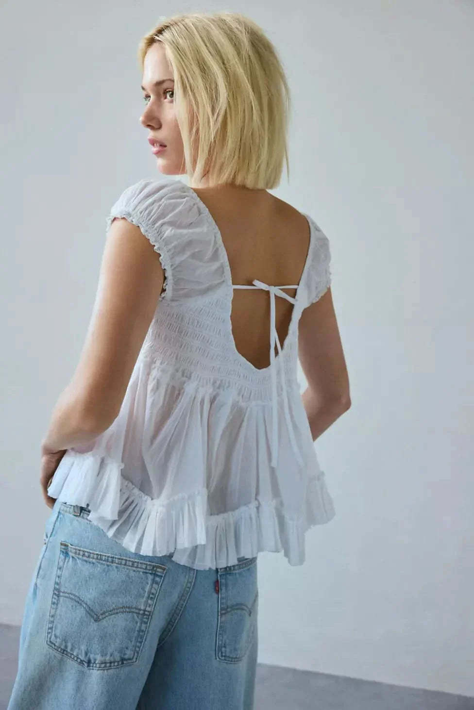 Tie-back detail on white lace top showing smocked bodice and open back design