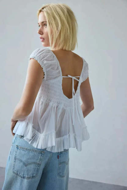 Tie-back detail on white lace top showing smocked bodice and open back design
