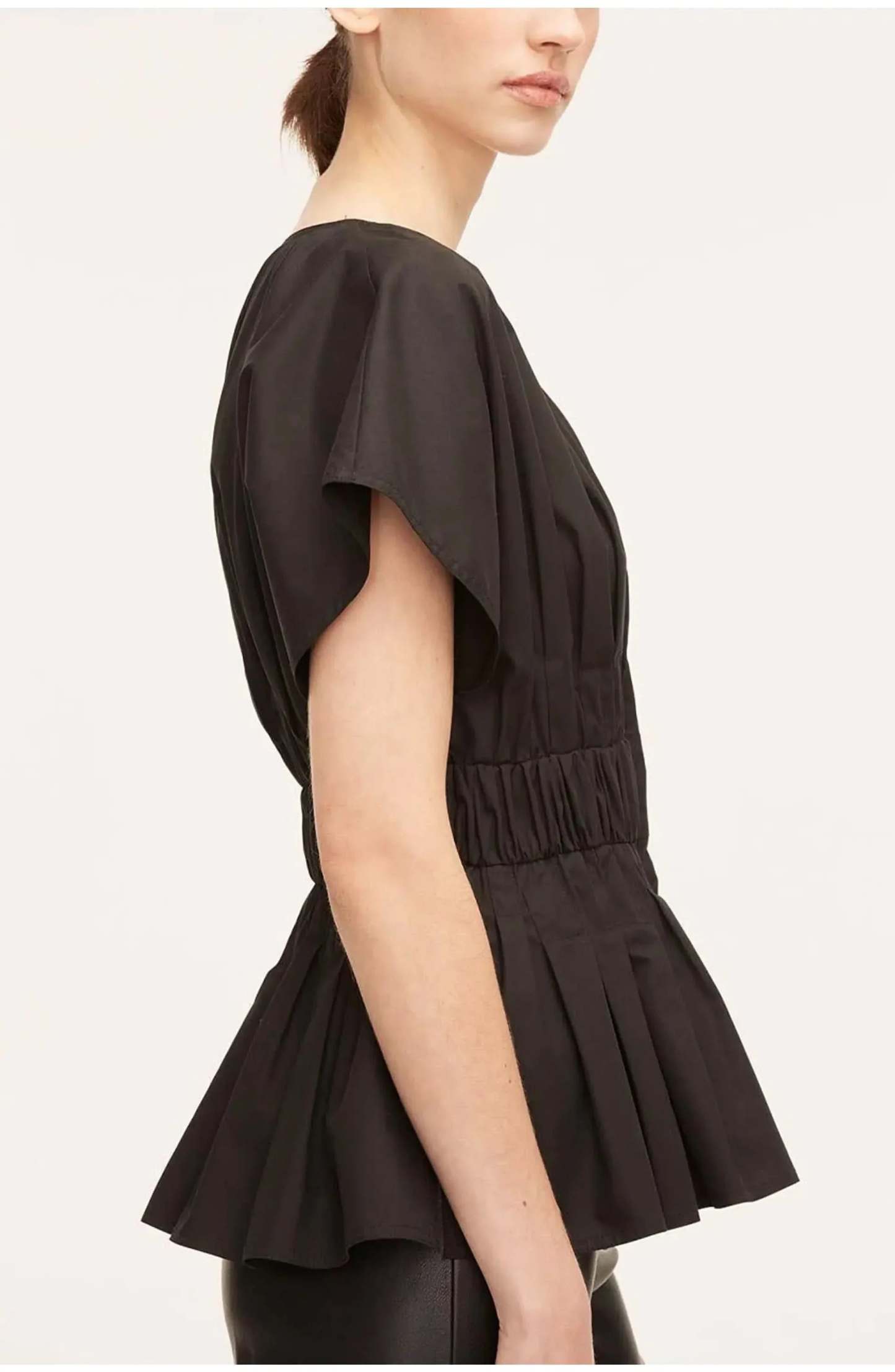 Side view of black peplum blouse showing structured hem and short sleeve detail