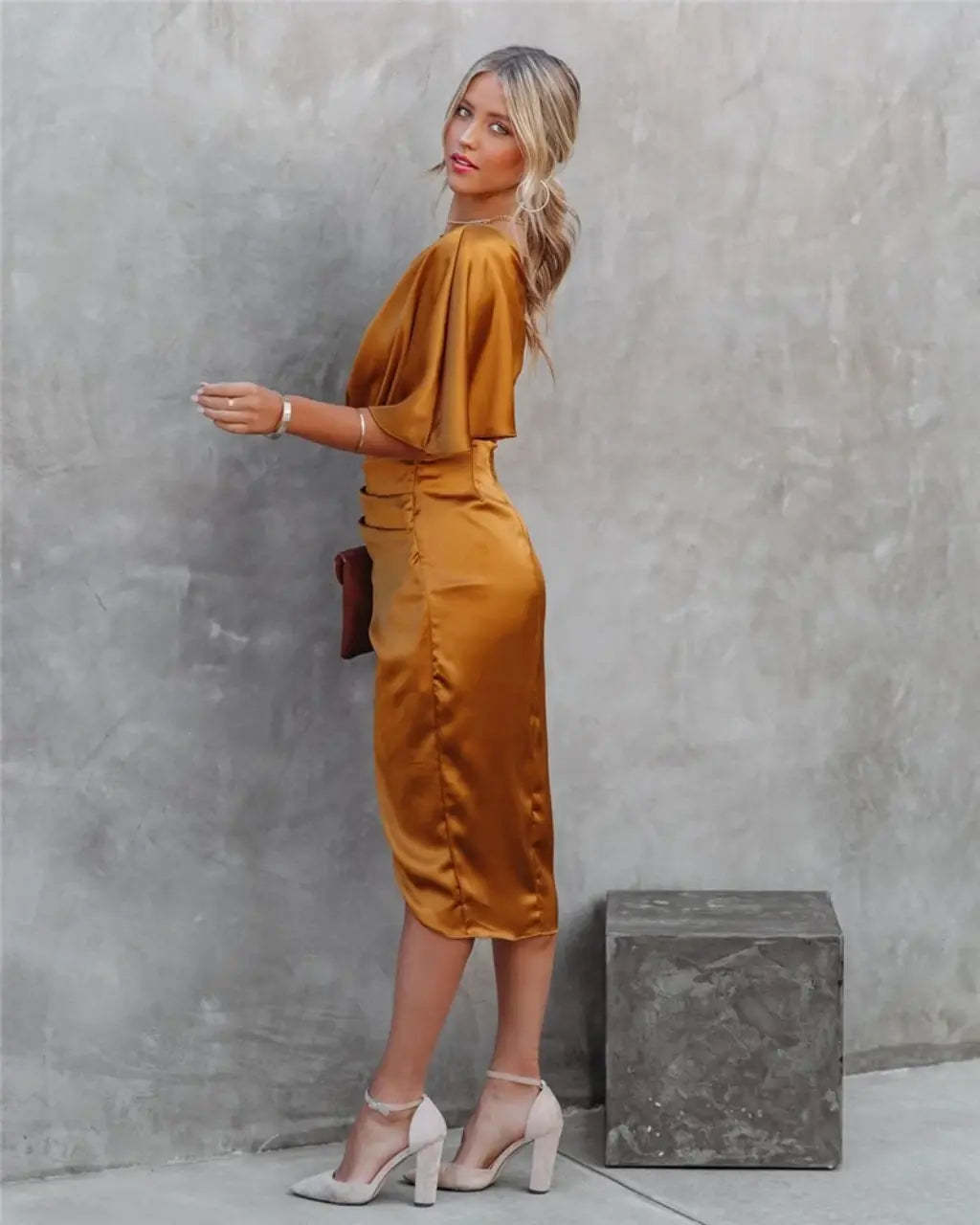 Back view of gold draped midi dress with flutter sleeve and ruched waist