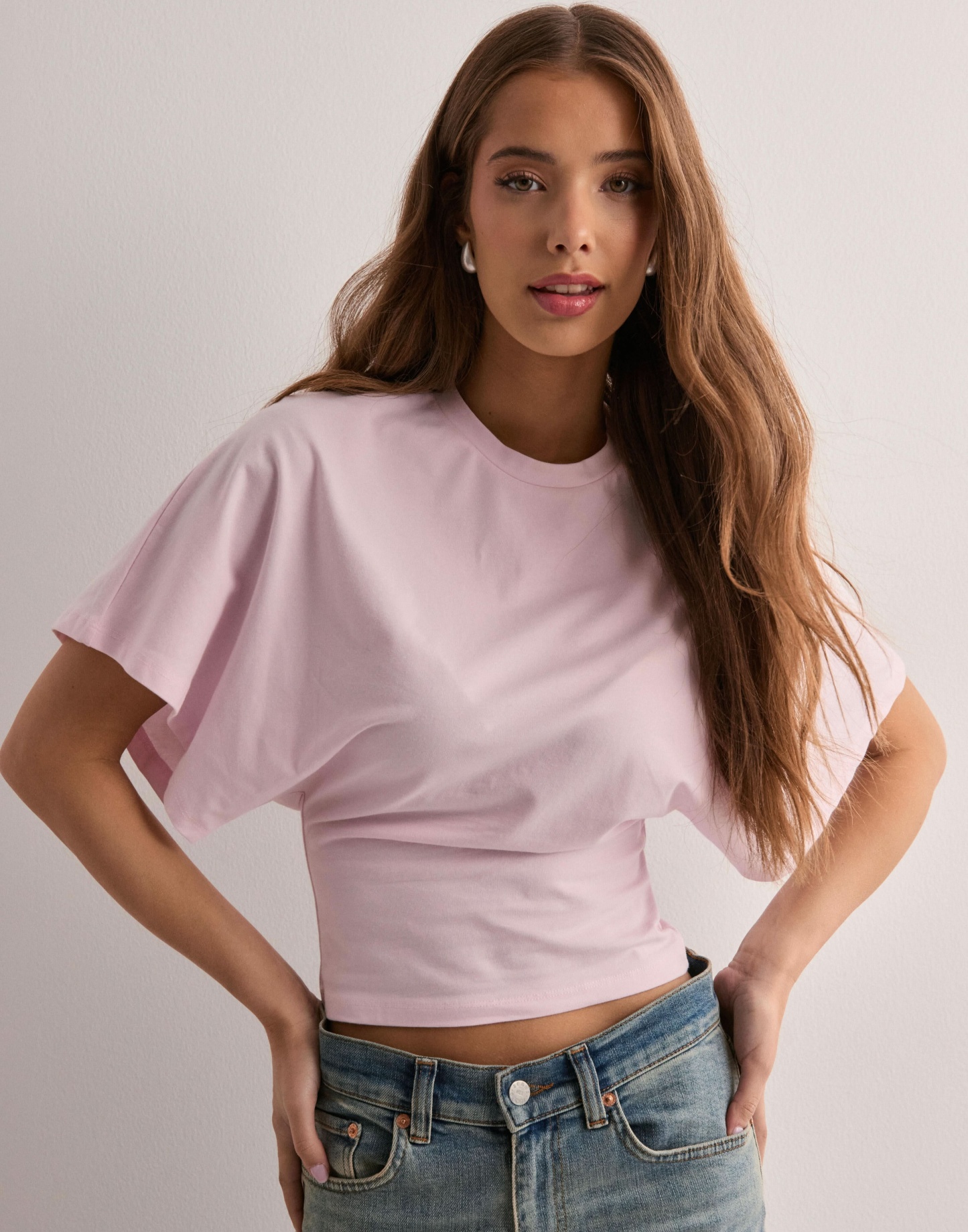 Light pink batwing crop top with relaxed short sleeves, side view