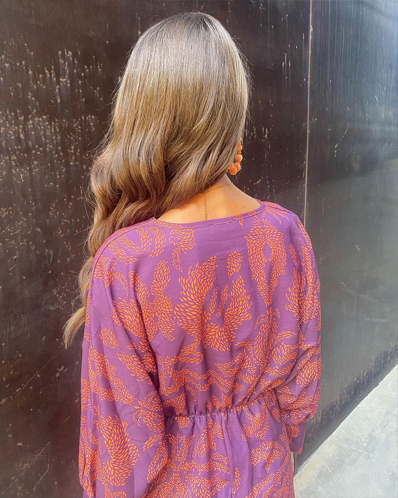Back view of purple wrap midi dress with orange feather print and long sleeves