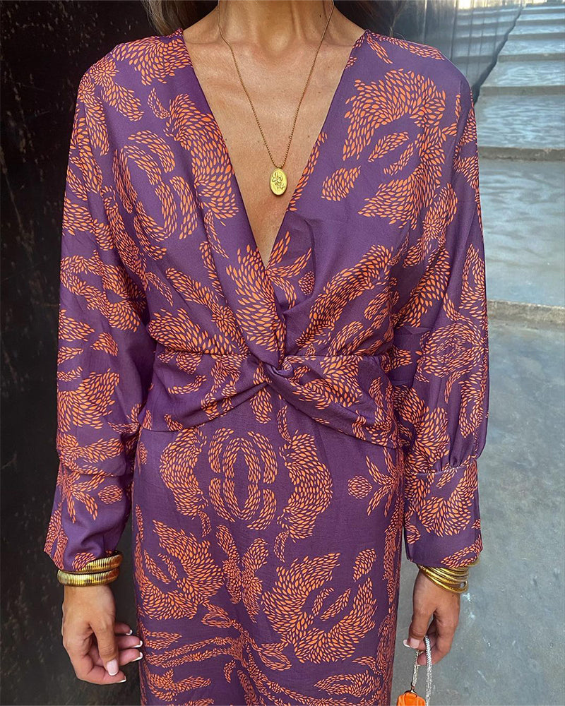 Front view of purple wrap midi dress with deep V-neckline and orange feather pattern
