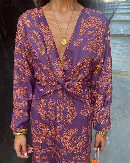 Front view of purple wrap midi dress with deep V-neckline and orange feather pattern