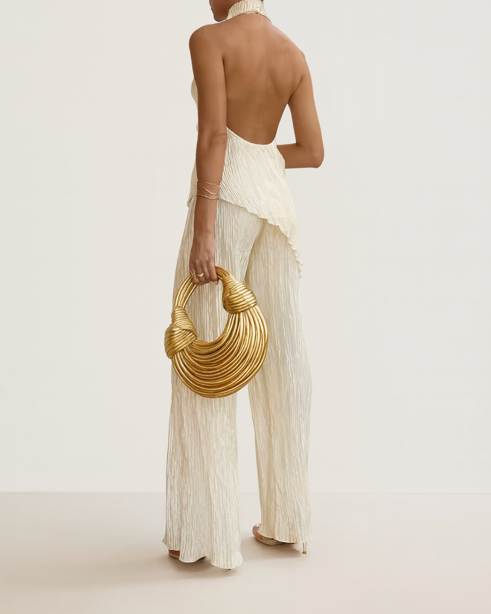 Back view of cream two-piece set showing dramatic open back halter top and pleated pants