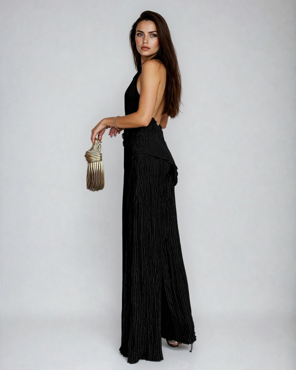 Side view of black pleated pants set showing backless halter design and draped silhouette