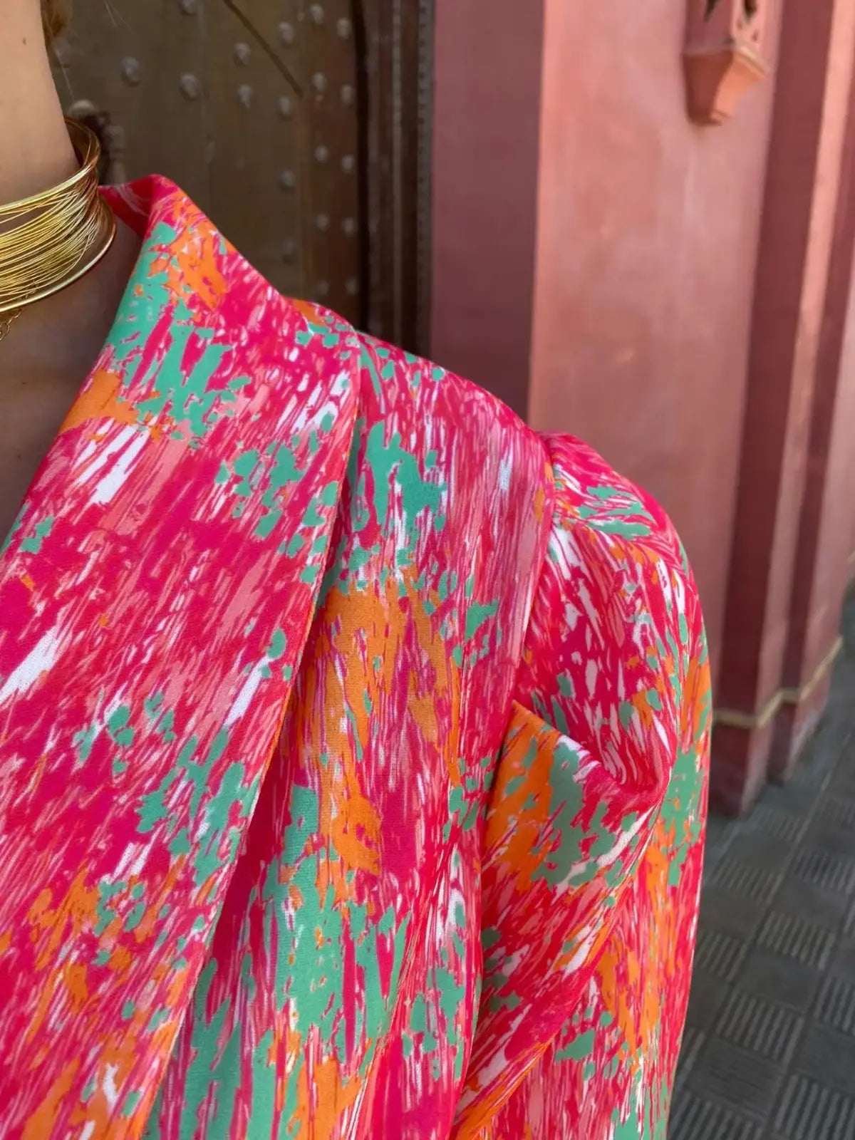 Close-up of crinkle texture and multicolor print on pink romper fabric