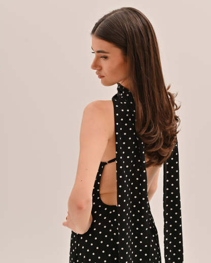 Back view of black polka dot maxi dress showing open backless design with tie straps