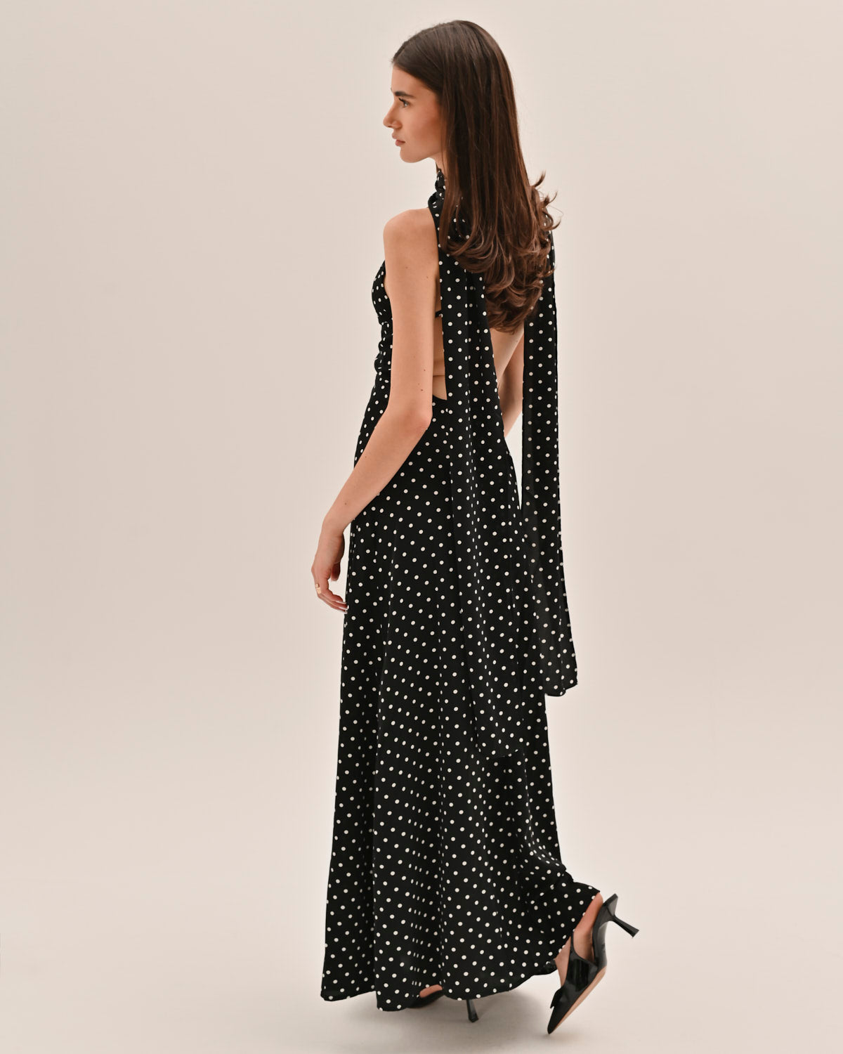 Side profile of black and white polka dot maxi dress with flowing fabric and long tie detail