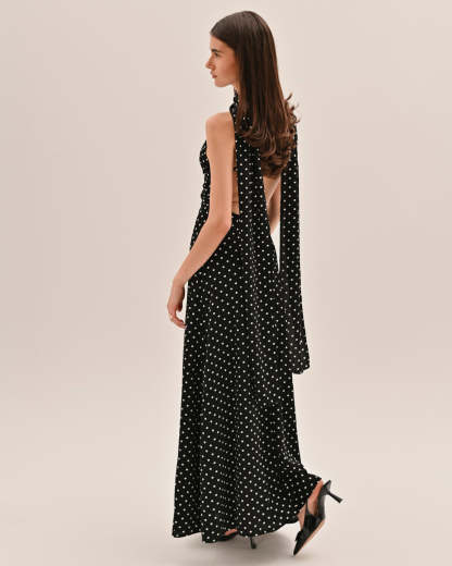 Side profile of black and white polka dot maxi dress with flowing fabric and long tie detail