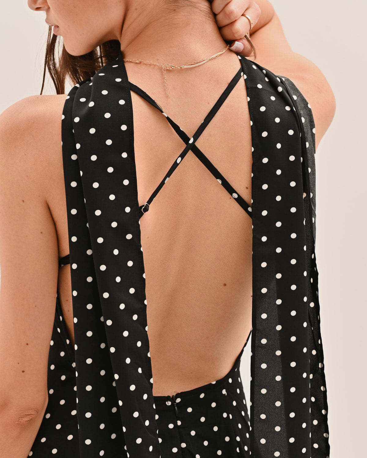 Close-up of backless maxi dress showing crossed tie straps and polka dot pattern detail