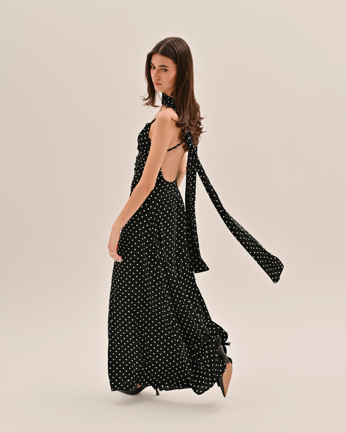 Back view of black polka dot maxi dress with open back and flowing tie straps