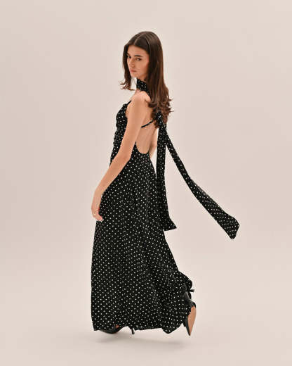 Back view of black polka dot maxi dress with open back and flowing tie straps