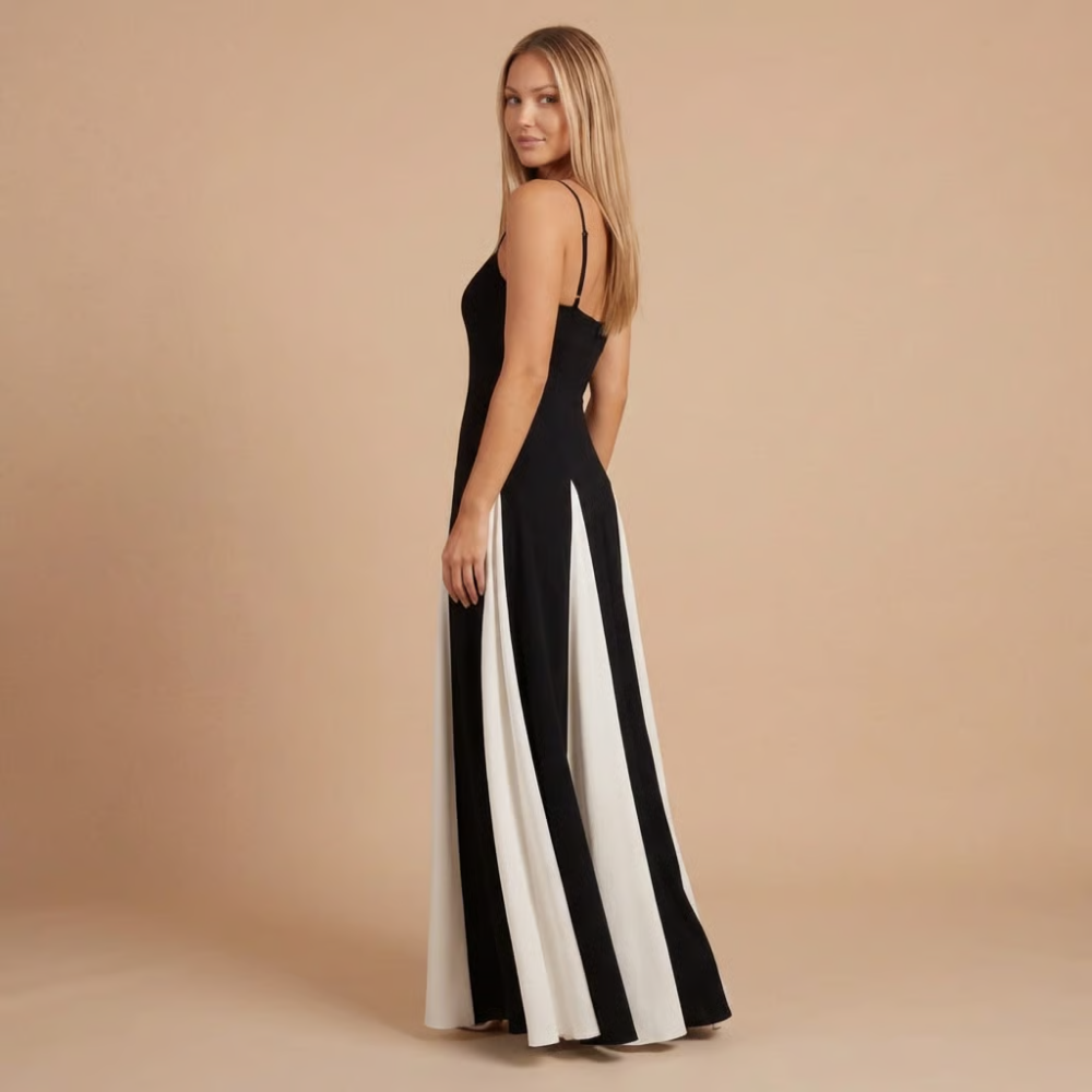 Side view of black maxi dress with white pleated contrast panels and floor-length hem